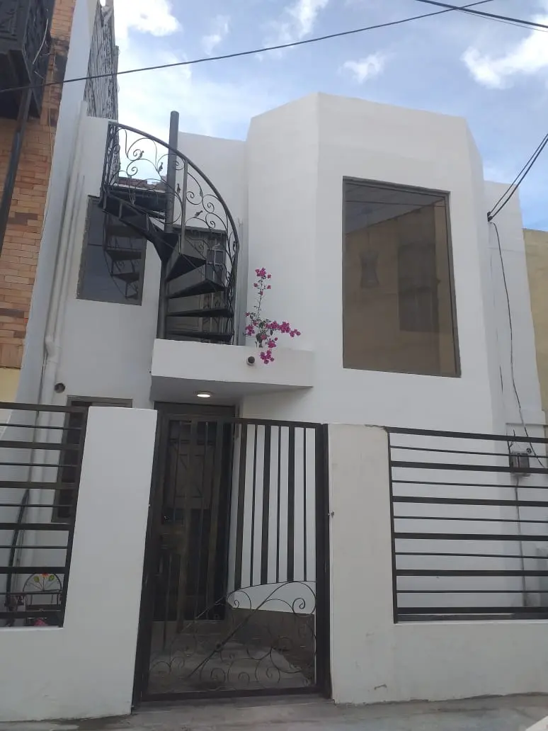 Fachada blanca de dos pisos de la casa Pinar en Riobamba, con escalera de caracol