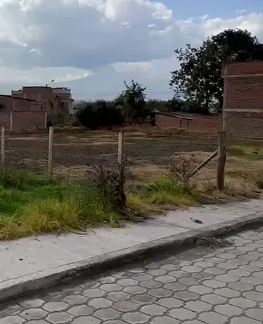 Lote esquinero de la lotización El Carmen en Chambo, con cerramiento y casas vecinas
