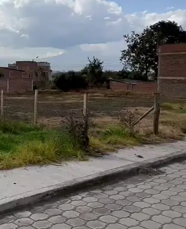 Lote esquinero de la lotización El Carmen en Chambo, con cerramiento y casas vecinas
