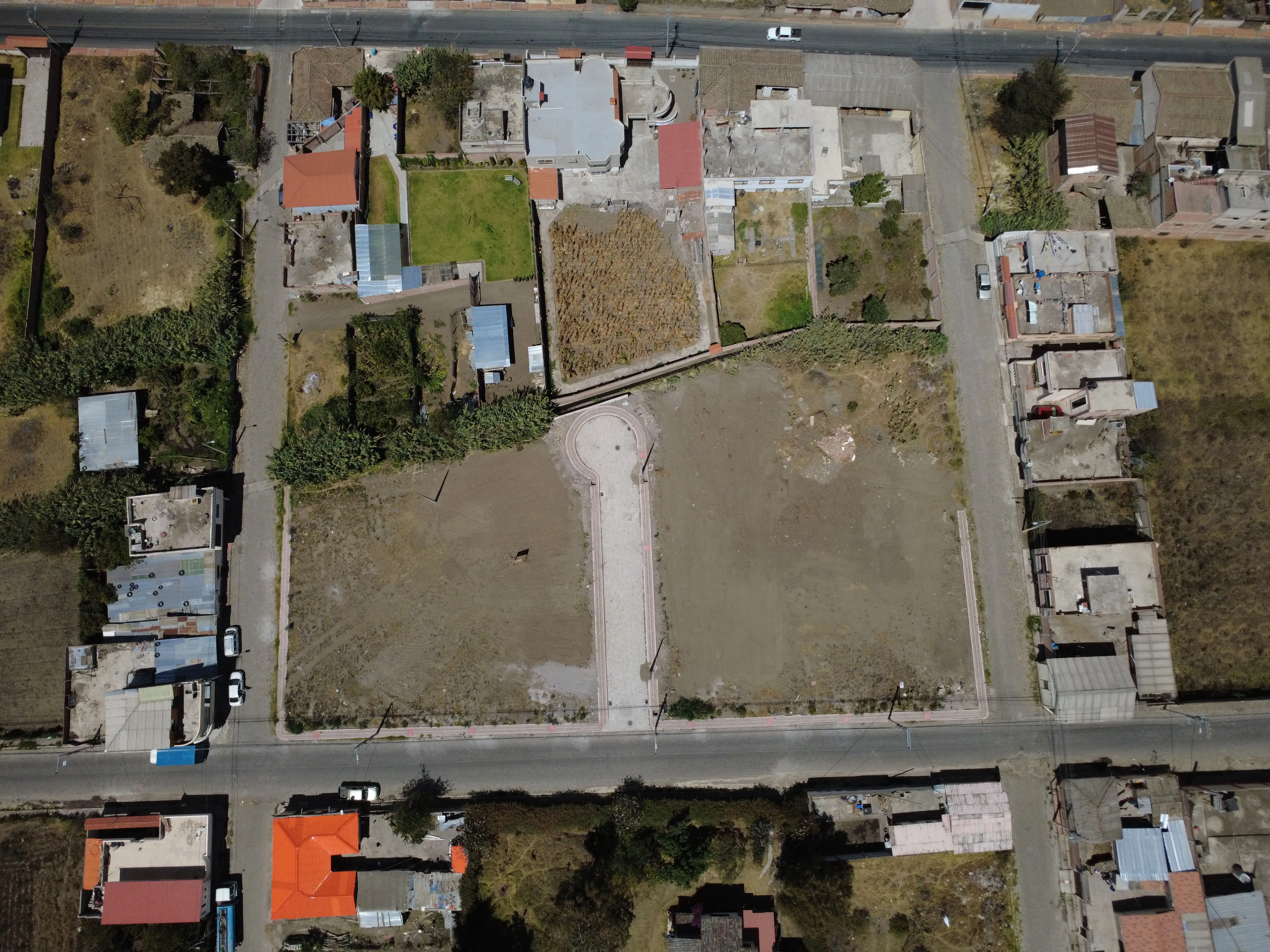 Vista aérea de los lotes de Emuná junto a la calle central adoquinada, con el valle de Guano alrededor