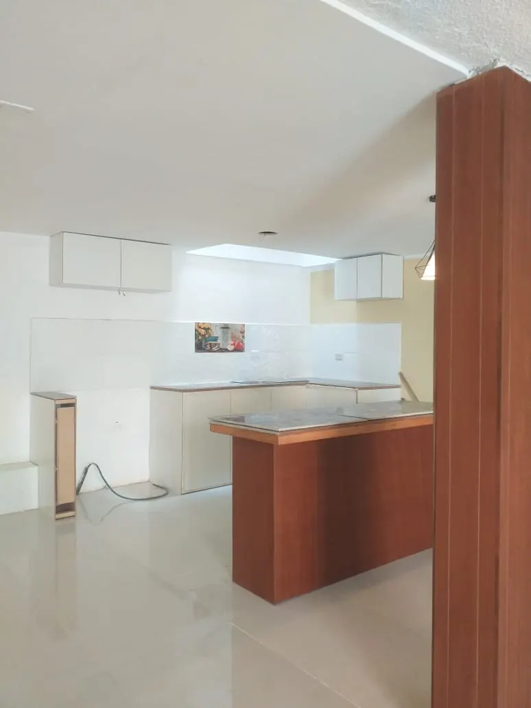 Cocina con barra de madera y muebles blancos en la casa Pinar