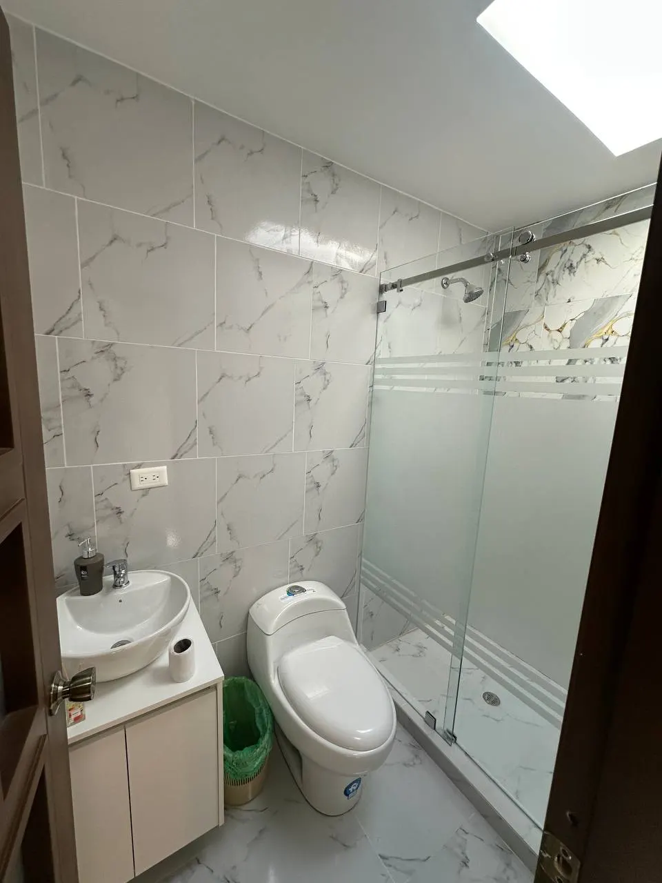 Baño con acabados de mármol y ducha de vidrio en Los Prematuros