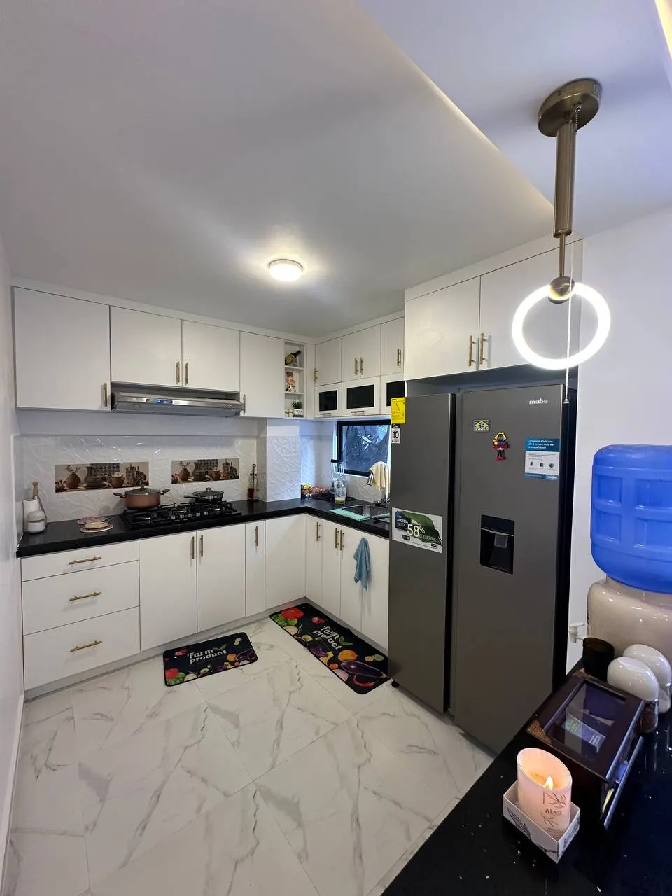 Cocina equipada con muebles blancos y refrigeradora en una casa de Los Prematuros