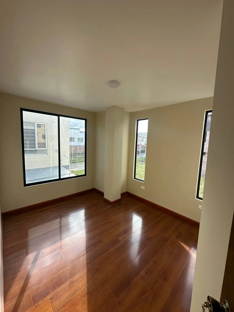 Dormitorio luminoso con piso de madera y ventanales en Los Prematuros